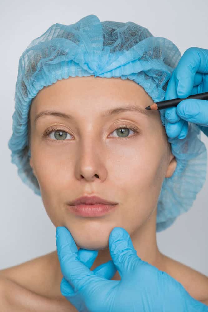 Cosmetic surgeon performing brow lift consultation for eye and face rejuvenation.